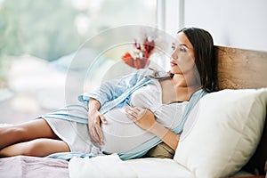 Portrait of happy pregnant woman relax lying in bed and touching her belly at home.