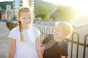 Portrait of a happy preteens girl and boy on a city street during a summer sunset. Friends are walking together. First love