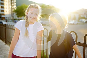 Portrait of a happy preteens girl and boy on a city street during a summer sunset. Friends are walking together. First love photo