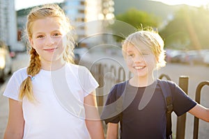 Portrait of a happy preteens girl and boy on a city street during a summer sunset. Friends are walking together photo