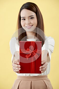 Portrait of a happy pretty asian woman holding present box while standing