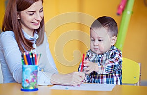 Portrait of happy pretty mother with her toddler son drawing