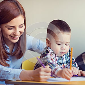 Portrait of happy pretty mother with her toddler son drawing