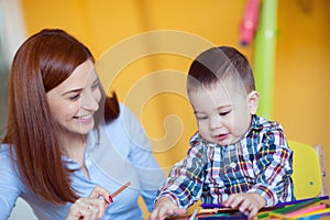 Portrait of happy pretty mother with her toddler son drawing