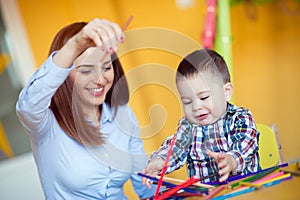 Portrait of happy pretty mother with her toddler son drawing