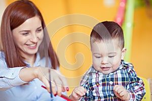 Portrait of happy pretty mother with her toddler son drawing