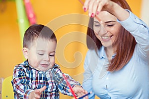 Portrait of happy pretty mother with her toddler son drawing