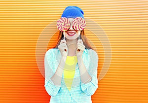 Portrait happy pretty smiling woman and lollipop having fun over colorful orange