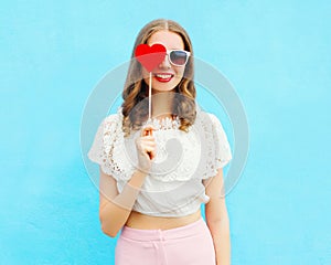 Portrait happy pretty smiling woman and lollipop over colorful blue