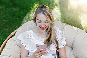 Portrait of a happy pretty woman using mobile phone outdoor. Bright sunny day