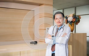 Portrait of happy professional asian man doctor standing and arms crossed with looking at camera in hospital