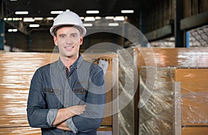 Portrait of happy professional handsome engineer man wearing safety white helmet standing arms crossed in logistics warehouse