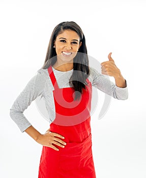 Portrait of a happy proud beautiful latin woman wearing a red apron learning to cook making thumb up gesture in cooking classes