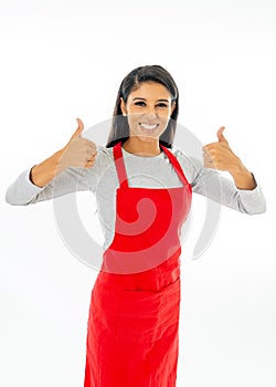 Portrait of a happy proud beautiful latin woman wearing a red apron learning to cook making thumb up gesture in cooking classes