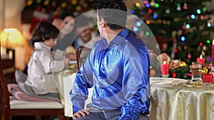 Portrait of happy proud handsome Middle Eastern man posing on Christmas at home indoors looking back at family turning