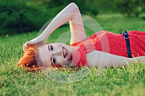 Portrait of a happy relaxed woman lying on grass looking and smiling