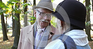 Portrait of happy retired family couple talking emotionally during walk in park