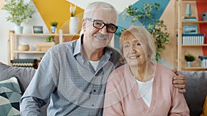 Portrait of happy retired people couple looking at camera and smiling at home