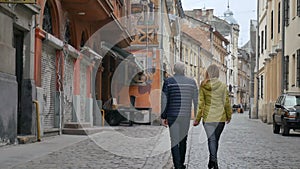 Portrait of happy romantic couple with age difference walking outdoors in the ancient city during early spring or autumn