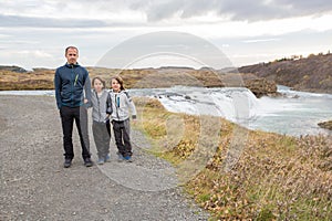 Portrait of happy running kids, boy brothers, near smaller waterfall around Gullfoss, Iceland