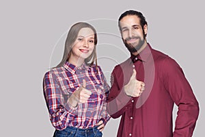 Portrait of happy satisfied bearded man and woman in casual style standing and looking at camera, smiling with thumbs up.