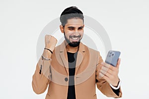 Portrait of a happy satisfied indian man looking at mobile phone and shouting isolated over white background