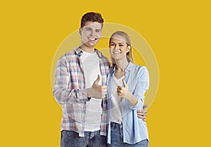 Portrait of happy satisfied young man and woman smiling and giving thumbs up together