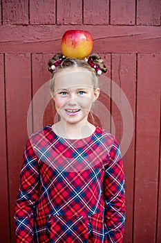 Portrait of a happy school girl with red apple on head. Farewell Bell. day of knowledge. beginning of the school year