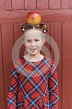 Portrait of a happy school girl with red apple on head. Farewell Bell. day of knowledge. beginning of the school year