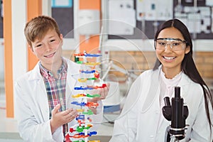 Portrait of happy school kids experimenting molecule model in laboratory