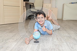 Portrait of a happy schoolboy studying a globe in the room