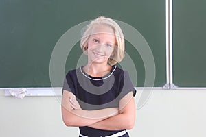 Portrait of happy schoolgirl 9-11 years old in a classroom near a chalkboard. Back to school.