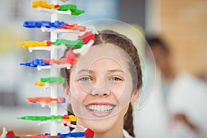 Portrait of happy schoolgirl experimenting molecule model in laboratory