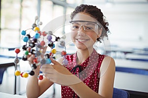 Portrait of happy schoolgirl experimenting molecule model in laboratory