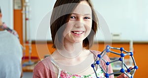 Portrait of happy schoolgirl experimenting molecule model in laboratory