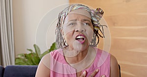 Portrait of happy senior african american woman making video call at home, unaltered, in slow motion