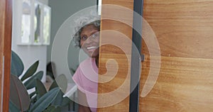Portrait of happy senior african american woman opening door at retirement home