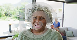 Portrait of happy senior african american woman with other seniors at retirement home