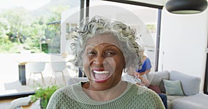 Portrait of happy senior african american woman with other seniors at retirement home