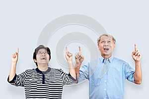 Portrait of happy senior asian couple gesture or pointing hand and finger up and looking at above on background feeling p