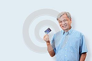 Portrait of happy senior asian man holding credit card and showing on hand smiling and looking at camera on isolated background f