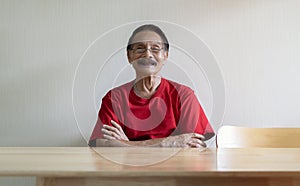 Portrait of happy senior Asian man sitting at wooden table with arm cross and looking at camera