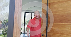 Portrait of happy senior biracial man opening door at retirement home