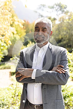 Portrait of happy senior biracial man smiling in sunny garden at home