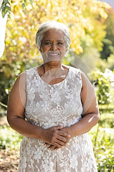 Portrait of happy senior biracial woman smiling in sunny garden at home