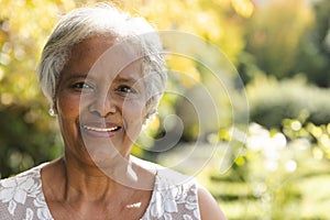 Portrait of happy senior biracial woman smiling in sunny garden at home, copy space