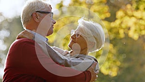 Portrait of happy senior Caucasian couple hugging in the park looking at each other elderly people wellbeing concept