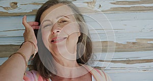 Portrait of happy senior caucasian woman laughing by weathered blue wooden wall, in slow motion