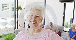 Portrait of happy senior caucasian woman with other seniors at retirement home