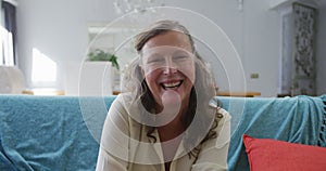 Portrait of happy senior caucasian woman sitting in living room smiling